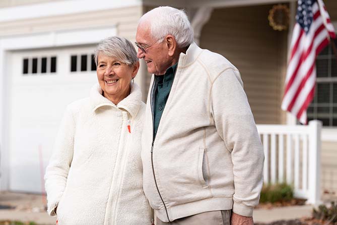 Happy older male and female couple outside house