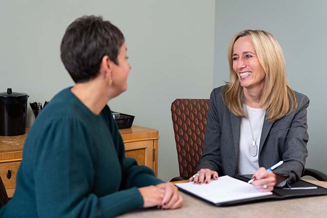 Two women talking at a desk in office