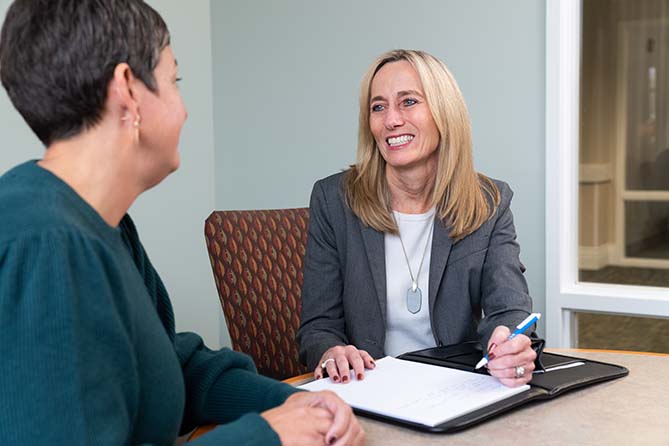 Two woman in an office talking and smiling