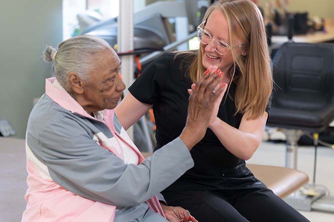 happy nurse high fives with patient in residential care home